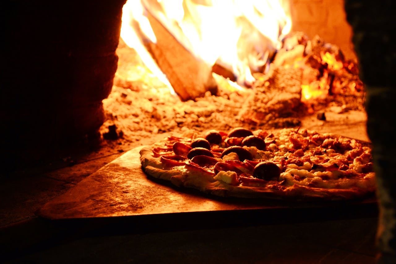 services-02 Delicious pizza baking in a traditional wood-fired oven with vibrant flames.