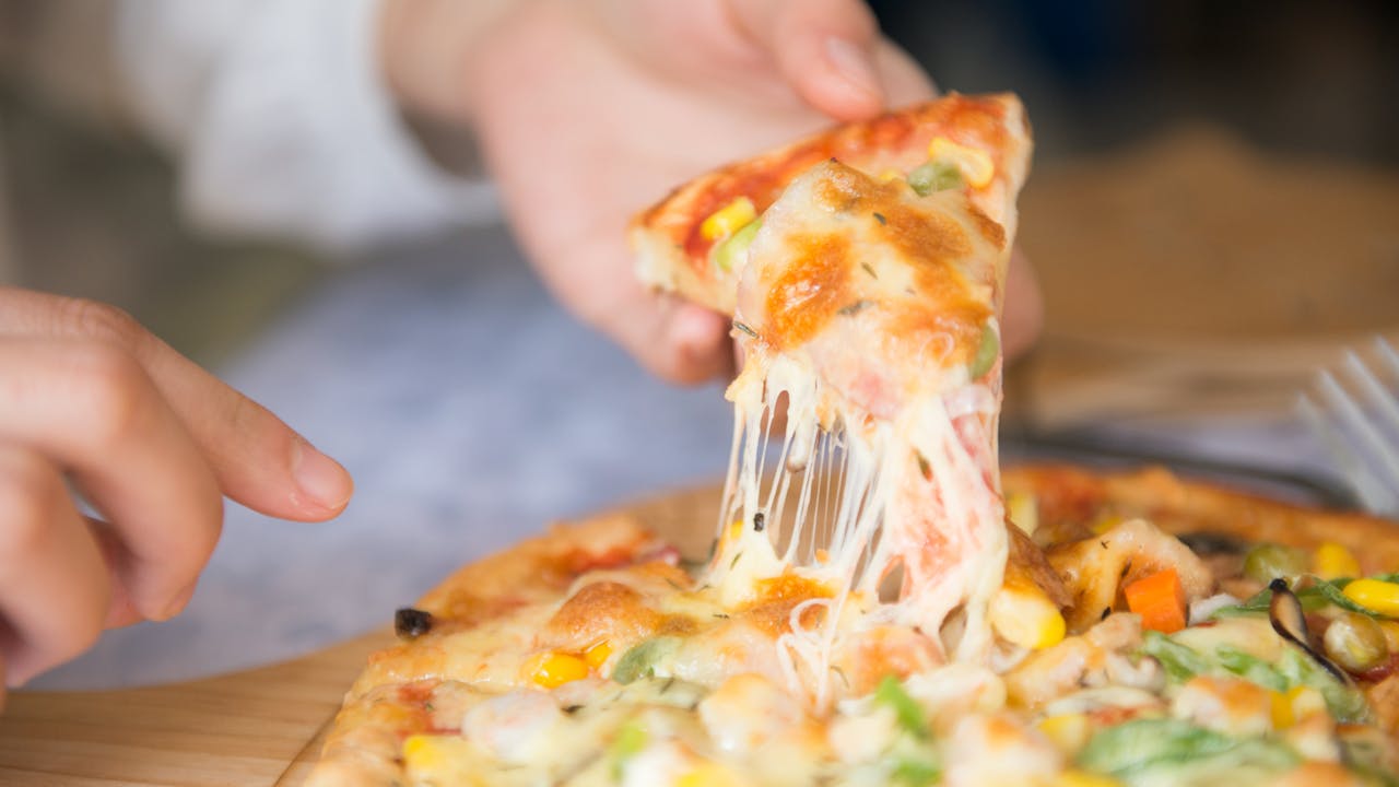 services-03 Appetizing close-up of a cheesy pizza slice with toppings, being pulled from a freshly baked pie.