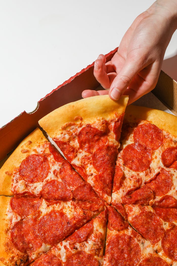Mastering the First Impression: Your intriguing post title goes here Close-up of a hand picking a pepperoni pizza slice from a box.
